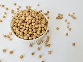 Raw dry chickpea in small ceramic bowl on white background. Traditional ingredient for cooking hummus. Middle Eastern and Mediterranean cuisine. Selected focused photo