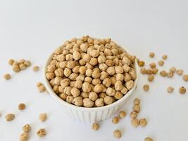Raw dry chickpea in small ceramic bowl on white background. Traditional ingredient for cooking hummus. Middle Eastern and Mediterranean cuisine. Selected focused photo
