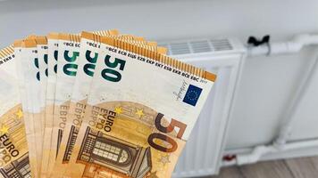 Close-up of a woman hands with banknotes of money in her hands next to a heating radiator. Increase in heating prices in selected households in Europe photo