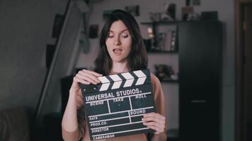 A beautiful girl holds a Clapperboard in her hands. Claps. Clicks. Winks at the camera. video