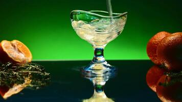 Drink with oranges and bright light on background is poured into glass. Stock clip. Bar atmosphere and alcoholic drink with fruit. Carbonated drink with fruit around is poured into transparent drink video