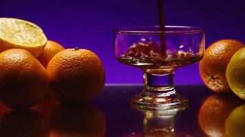 Whisky is poured into the glass on a colorful wall background. Stock clip. Oranges lying on a table at the night club. video