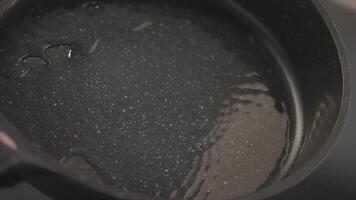 Close-up rotation of frying pan with oil. Action. Distribution of oil in pan. Heating oil in new frying pan for cooking video