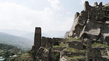 Top view of historical stone ruins on background of mountains. Action. Cinematic view of ancient stone ruins in mountains. Stone ruins of ancient city on green mountains on sunny day video