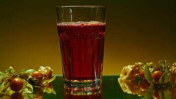 Refreshing carbonated beverage in transparent glass with berries isolated at colorful wall background. Clip stock. Cool cola soda drink at bar counter with berries. video