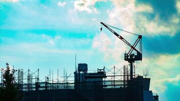 A timelapse of moving cranes at top of the building in Tokyo tilt video
