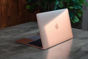 an apple laptop is on the table in light, photo