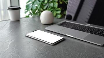 phone and laptop on table with plants in background, photo