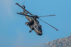 an army helicopter flying high through the blue skies, photo