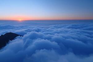 the sunset is setting above two mountain tops surrounded by clouds, photo
