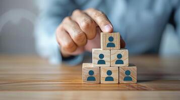two hands stacking wooden blocks with blue people image on them, photo