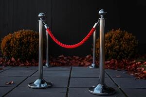 two metallic posts and red rope outside a building, photo