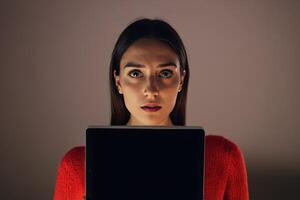 a woman posing holding a computer and looking at the screen, photo
