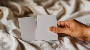 a person holding up two cards that are on a bed, photo