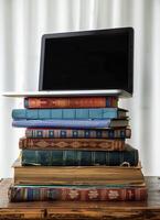 a stack of old books and a laptop computer on top of one, photo