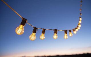 string of lights hanging high in the sky above a field, photo