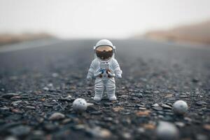 small action figure in open space on asphalt surface, photo