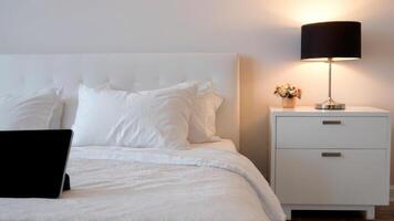 an unmade bed with flowers and pillows beside a lamp, photo