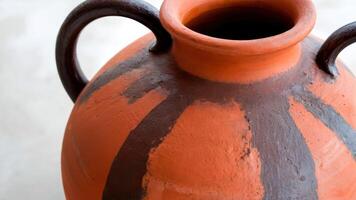 an orange vase with metal handles is painted like lines, photo