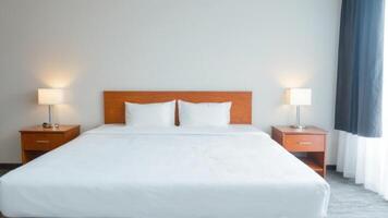 a neatly made bed with two bedside lamps on either side, photo