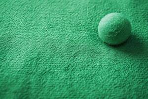 the ball is lying on the green carpet, photo
