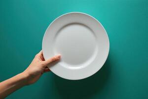 a woman holding an empty white plate next to two fingers, photo