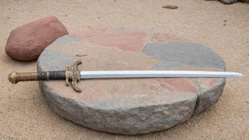 a small, ornate dagger with decorative bits near large stone, photo