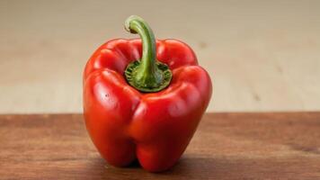 an uncooked red bell pepper sitting on top of a wooden cutting board, photo