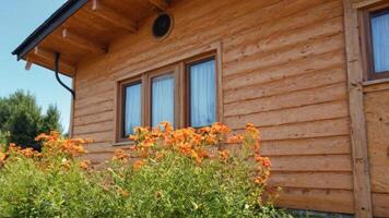 a house with a wooden roof, flowers and trees, photo