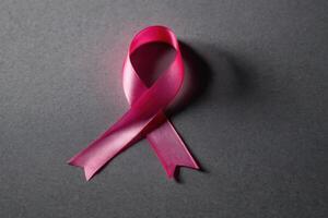 the end of a pink ribbon laying on to the surface, photo