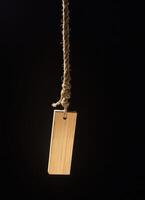 a wooden tag is suspended from a rope, photo