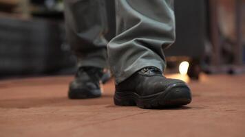 close-up of the legs of a worker, mechanic, builder at a factory, in a garage video