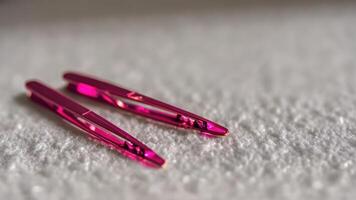 two pink metallic hair clip laying on top of a blanket, photo