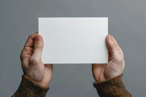 man holding up white square paper in both hands, photo