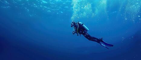 a woman scubas beneath blue water and another below, photo