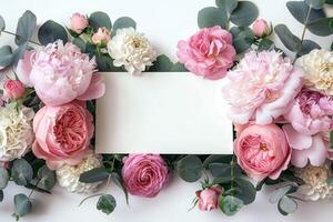 roses and foliage surround a business card that's on top of a white table, photo