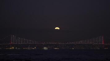 Night background of a big city and river. Action. Beautiful full moon hiding behind the clouds in the dark sky. video