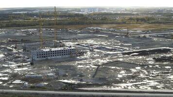 Aerial view of a construction site outside the city. Stock footage. Process of building construction surrounded by grove of green trees. video