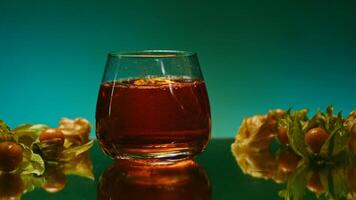 A bright illuminated still life. Stock clip . A beautiful roomy mug in which brandy is poured and small oranges and tangerines lie next to it. video