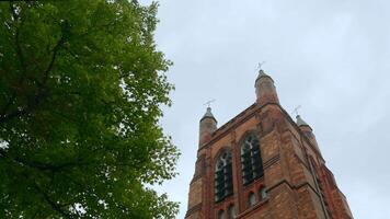 Low angle view of a beautiful red brick building with towers. Action. Concept of architecture, street of an old city. video