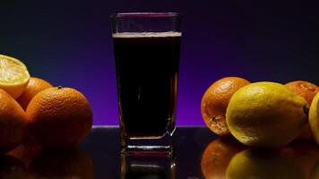 Dark drink with citrus fruits around. Stock clip. Drink with foam on background of citrus fruits and isolated background. Bar drink with citrus fruits video