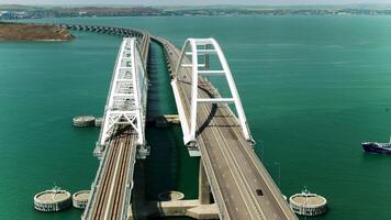 Huge bridges for movement . View from a helicopter . Shot .Two huge long bridges located high above the sea, ships floating are visible, residential buildings on the shore and the blue sky are visible video