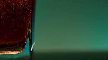 Close up of red soft drink inside a glass against a wall changing color. Stock clip. Bubbles of air inside a glass of soda. video