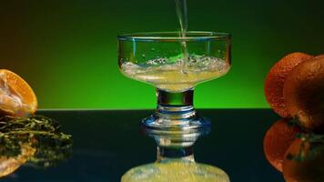 Close up of pouring orange soda into the glass. Stock clop. Soft drink with the taste of citrus and orange fruits on the reflective table surface. video