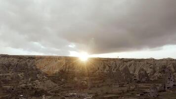 Grey landscape from a bird 's - eye view . Action . The bright sun is shining directly into the camera and a deserted forest with mountains is visible. video