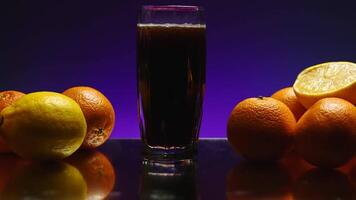 The concept of a bartender. Stock clip.Purple illuminated background with a large roomy glass in which soda is poured and the whole still life is decorated with light oranges video