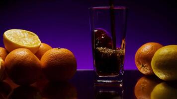 The concept of a bartender. Stock clip.Purple illuminated background with a large roomy glass in which soda is poured and the whole still life is decorated with light oranges video