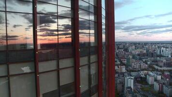 Aerial view of a modern glassed office skyscraper exterior with cityscape reflection in the windows. Stock footage. Flying above the modern city on a summer evening. video