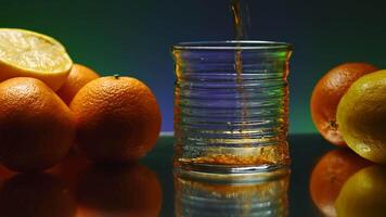 Drink on background of oranges is poured into transparent glass. Stock clip. Bar drink made of oranges. Oranges around glass with bar drink video