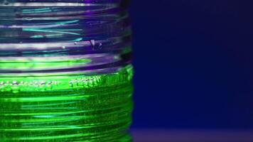 Soft drink of green color on blurred colorful wall background. Stock clip. Soda with bubbles in transparent glass. video